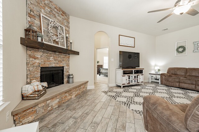 living room featuring a fireplace, light wood-type flooring, and ceiling fan