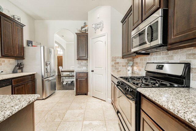 kitchen with light stone countertops, appliances with stainless steel finishes, backsplash, and light tile patterned floors