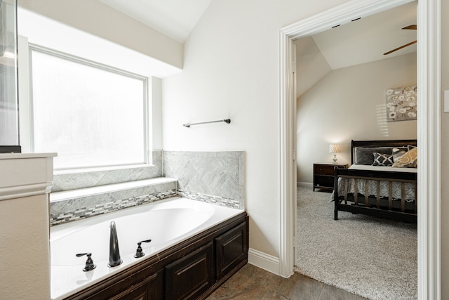 bathroom featuring a tub to relax in, vaulted ceiling, and ceiling fan