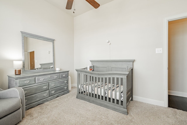 carpeted bedroom with ceiling fan and a crib