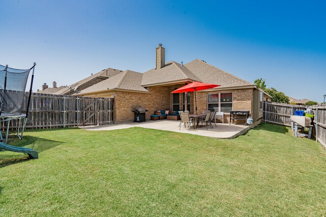 rear view of house featuring a trampoline, a patio, and a yard