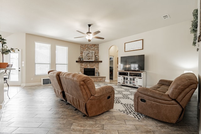 living room featuring ceiling fan, a fireplace, and light hardwood / wood-style flooring