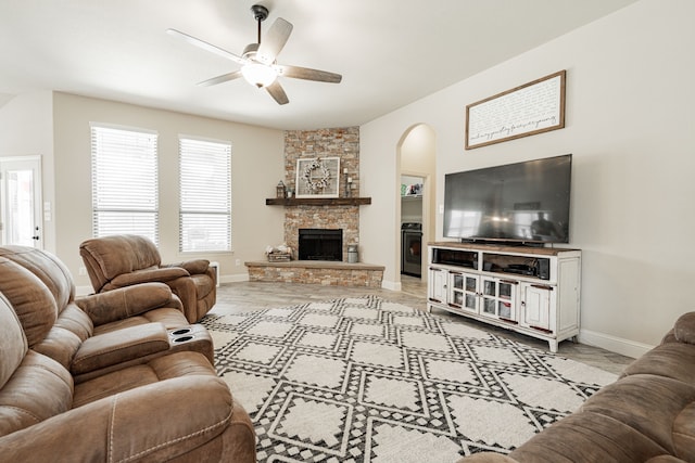 living room featuring ceiling fan and a stone fireplace