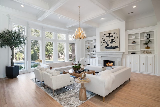 living room with built in features, beam ceiling, coffered ceiling, a notable chandelier, and light hardwood / wood-style floors