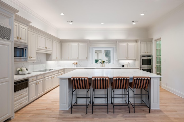 2 Manzano, Dallas, TX 75230 - kitchen featuring appliances with stainless steel finishes, a center island, a kitchen breakfast bar, a warming drawer, and light wood-style floors