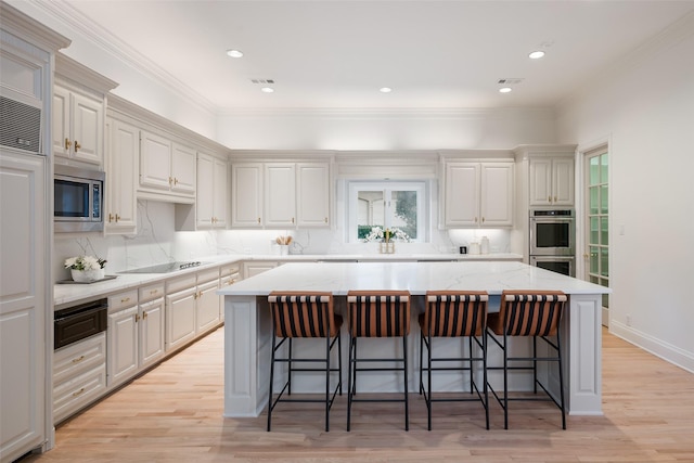 kitchen featuring a kitchen island, tasteful backsplash, a kitchen breakfast bar, stainless steel appliances, and light hardwood / wood-style flooring