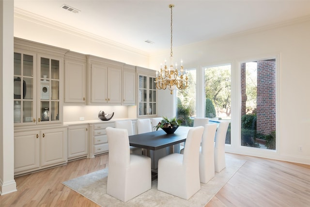 dining room with ornamental molding, light hardwood / wood-style floors, and a chandelier