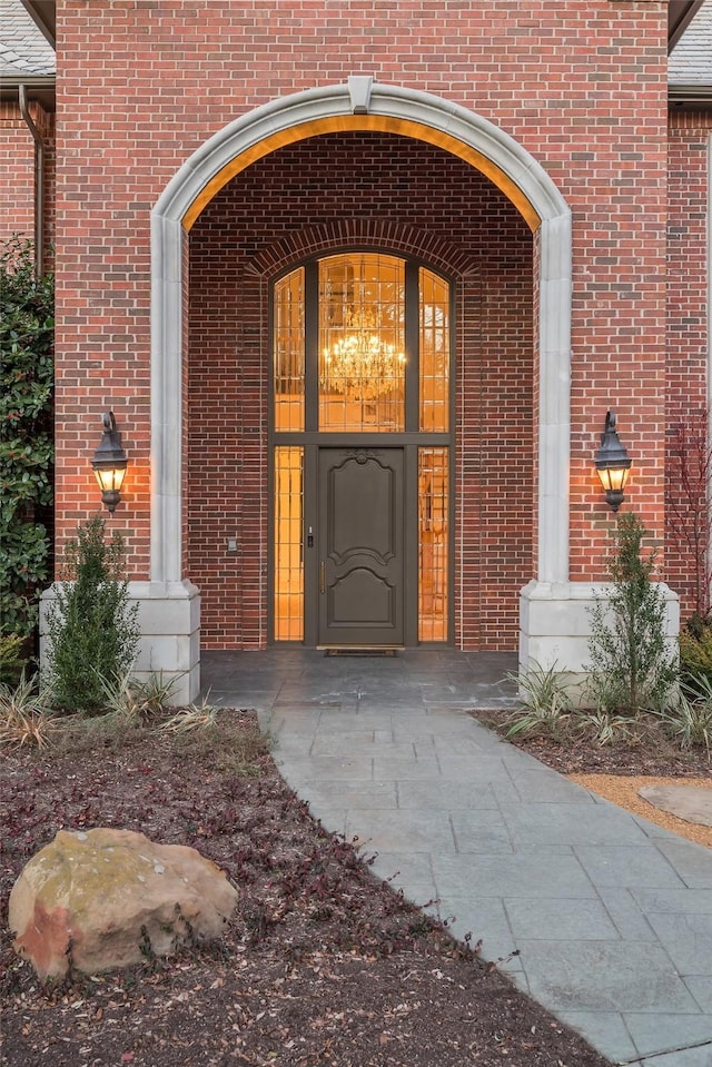 entrance to property with covered porch and brick siding