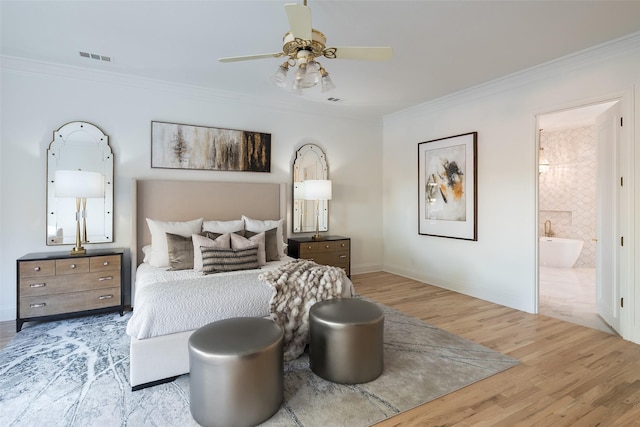 bedroom with light hardwood / wood-style floors, crown molding, and ensuite bathroom