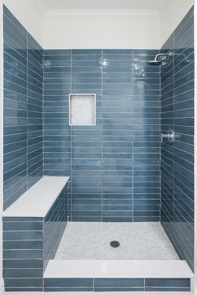 bathroom featuring ornamental molding and a tile shower