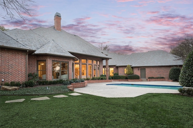 pool at dusk with a yard and a patio area