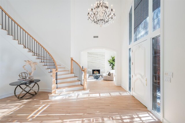 entryway with ornamental molding, light hardwood / wood-style floors, and a towering ceiling