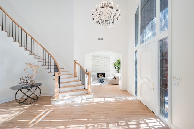 entrance foyer with hardwood / wood-style flooring, a high ceiling, an inviting chandelier, and a fireplace