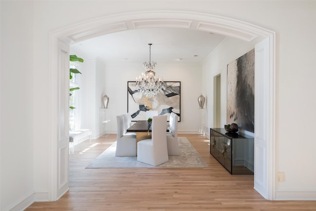 dining space featuring crown molding, an inviting chandelier, and light hardwood / wood-style floors