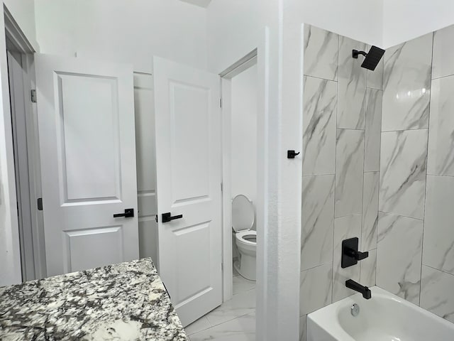 bathroom featuring tiled shower / bath combo and toilet