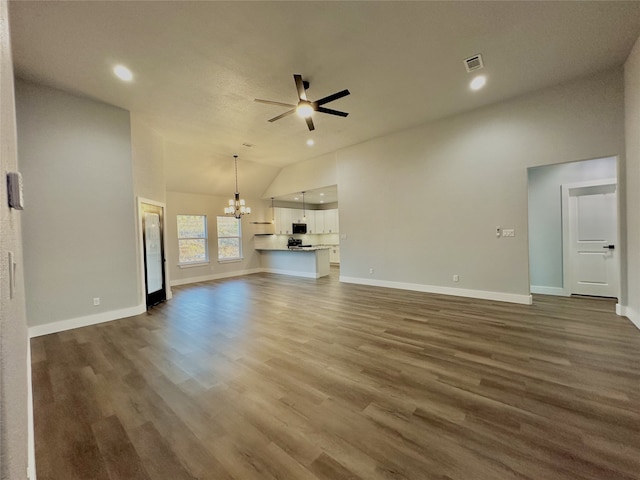 unfurnished living room with ceiling fan with notable chandelier, dark wood-type flooring, and lofted ceiling