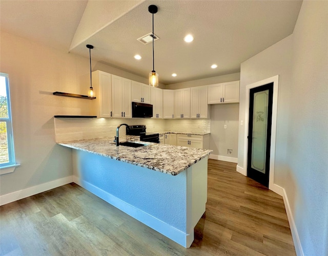 kitchen featuring sink, black appliances, light hardwood / wood-style floors, white cabinetry, and hanging light fixtures