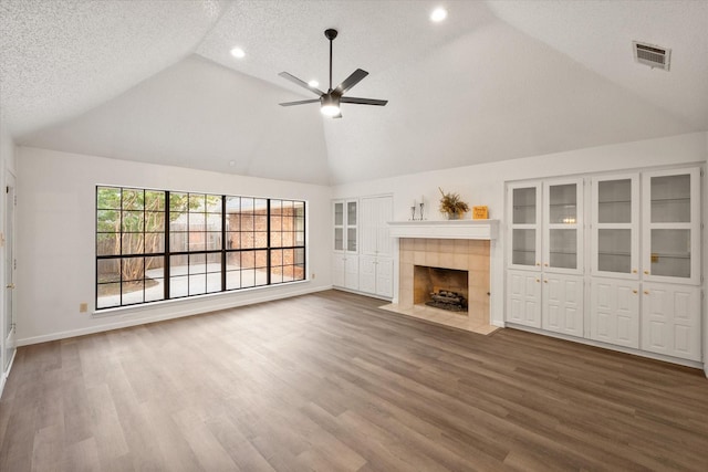 unfurnished living room featuring hardwood / wood-style flooring, a tile fireplace, and a textured ceiling