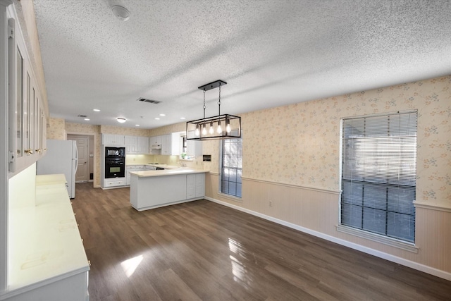 5400 Emerald Park Blvd, Arlington, TX 76017 - kitchen featuring freestanding refrigerator, black microwave, a wainscoted wall, a peninsula, and dark wood finished floors