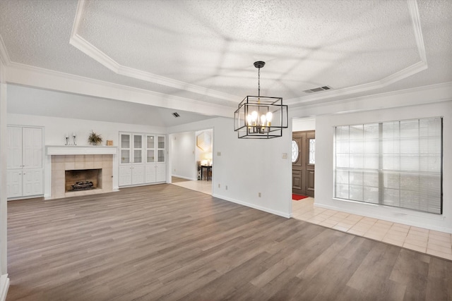 5400 Emerald Park Blvd, Arlington, TX 76017 - unfurnished living room featuring a textured ceiling, wood finished floors, a tray ceiling, a chandelier, and crown molding