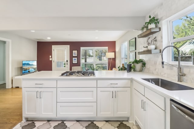 kitchen with kitchen peninsula, appliances with stainless steel finishes, white cabinets, and plenty of natural light