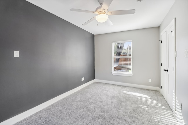 empty room featuring ceiling fan and light colored carpet