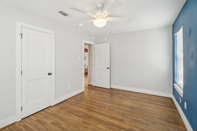 unfurnished bedroom featuring multiple windows, ceiling fan, and wood-type flooring