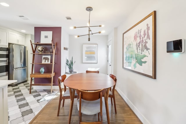 dining area featuring light hardwood / wood-style flooring and an inviting chandelier