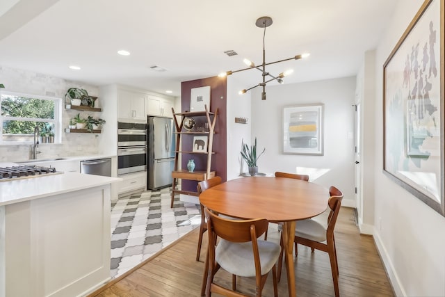 dining area featuring light hardwood / wood-style floors, a notable chandelier, and sink