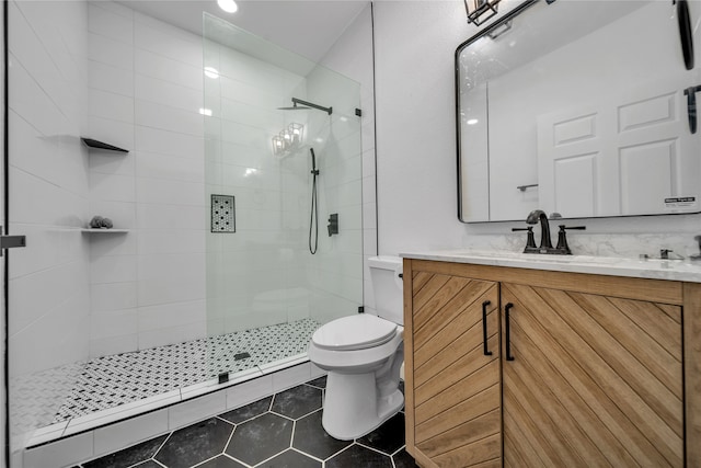 bathroom featuring a tile shower, vanity, toilet, and tile patterned floors