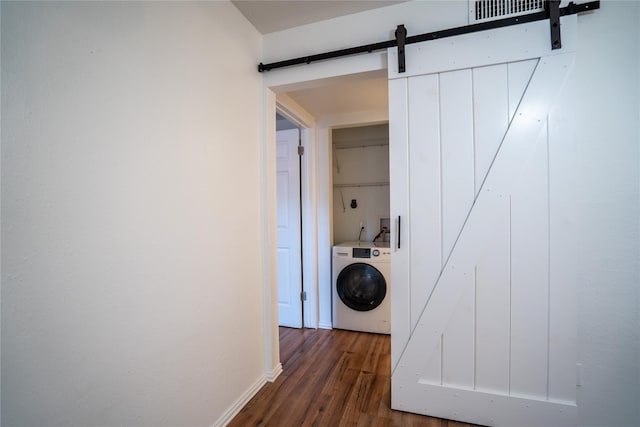 laundry area with a barn door, dark wood-type flooring, and washer / dryer