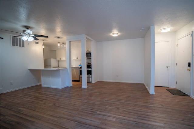 unfurnished living room with a textured ceiling, ceiling fan, and dark hardwood / wood-style floors