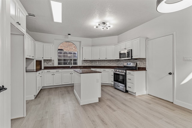 kitchen featuring white cabinetry, a kitchen island, light wood-type flooring, and appliances with stainless steel finishes