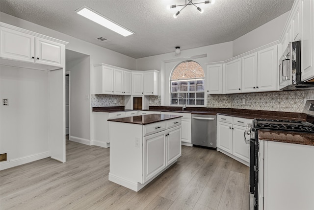 kitchen featuring a textured ceiling, white cabinetry, stainless steel appliances, and light hardwood / wood-style flooring