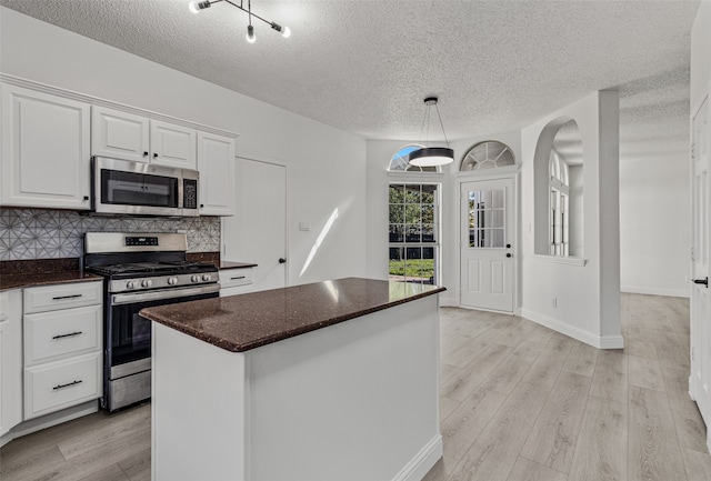 kitchen with white cabinets, a textured ceiling, appliances with stainless steel finishes, and light hardwood / wood-style flooring