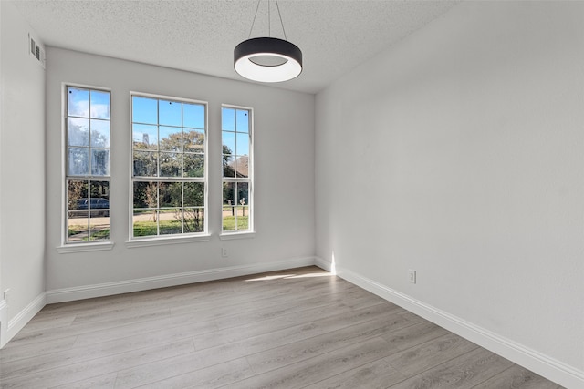 unfurnished room with a textured ceiling and light wood-type flooring