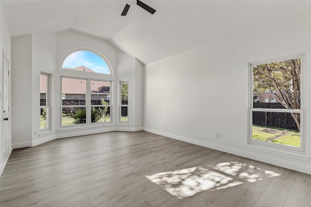 unfurnished living room with ceiling fan, light hardwood / wood-style flooring, high vaulted ceiling, and a textured ceiling