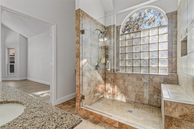 bathroom featuring walk in shower, a textured ceiling, sink, wood-type flooring, and lofted ceiling