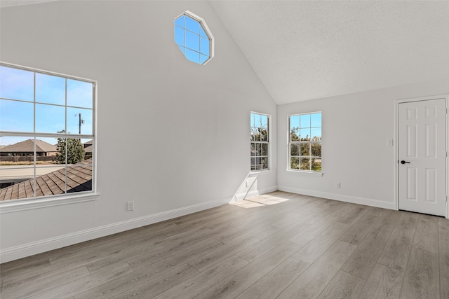 interior space featuring a textured ceiling, high vaulted ceiling, and light hardwood / wood-style flooring