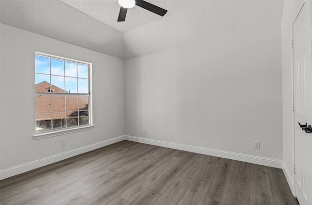 empty room with a textured ceiling, light wood-type flooring, ceiling fan, and lofted ceiling