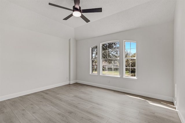 empty room with vaulted ceiling, ceiling fan, light hardwood / wood-style flooring, and a textured ceiling