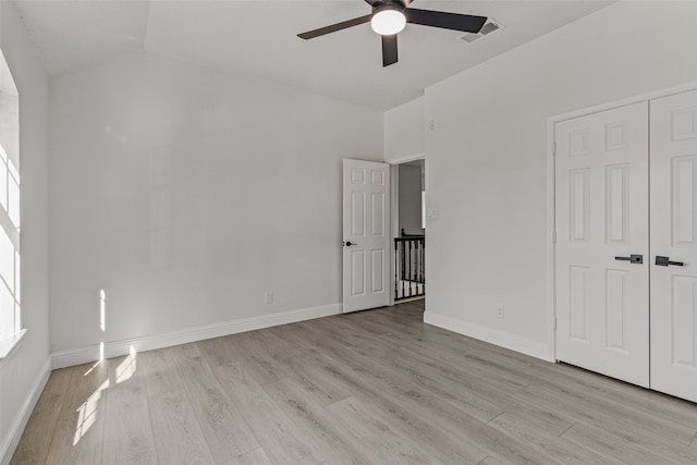 unfurnished bedroom with a closet, ceiling fan, light hardwood / wood-style flooring, and lofted ceiling