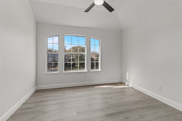 empty room featuring ceiling fan, light wood-type flooring, a textured ceiling, and lofted ceiling