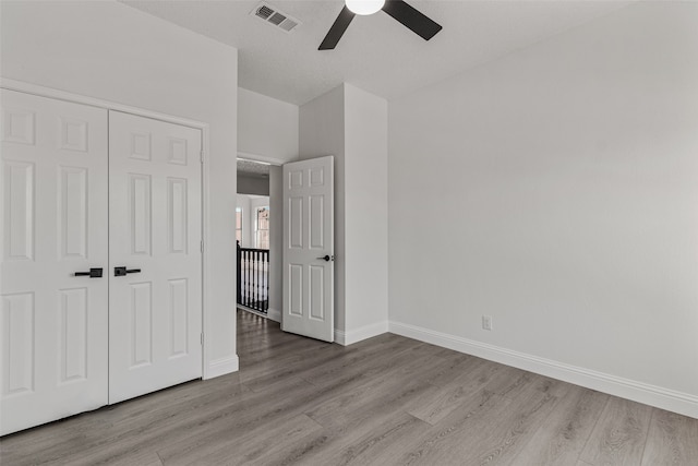 unfurnished bedroom featuring light hardwood / wood-style floors, a closet, and ceiling fan