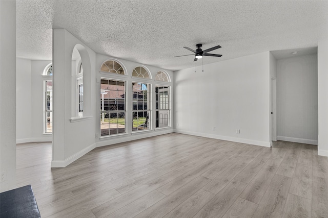 unfurnished living room featuring ceiling fan, light wood-type flooring, and a textured ceiling