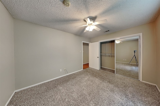 unfurnished bedroom with carpet, ceiling fan, a textured ceiling, and a closet