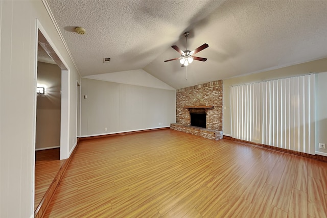 unfurnished living room featuring lofted ceiling, hardwood / wood-style flooring, ceiling fan, a fireplace, and a textured ceiling