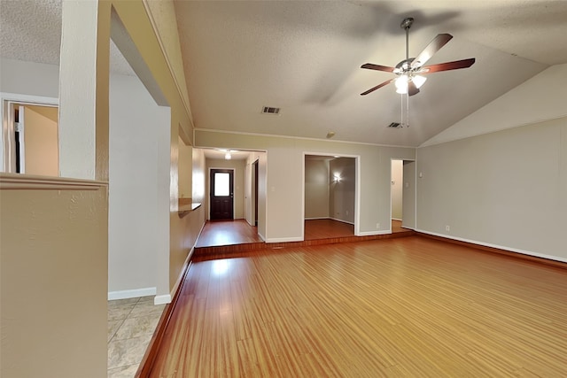 unfurnished living room featuring ceiling fan, lofted ceiling, a textured ceiling, and light hardwood / wood-style flooring