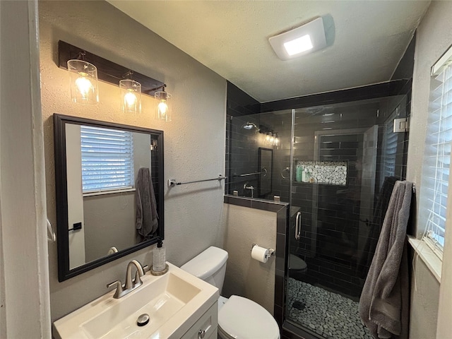 bathroom with toilet, a shower stall, vanity, and a textured wall