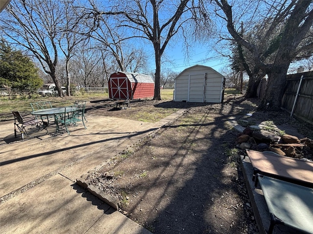 view of yard with a storage shed, a patio area, an outbuilding, and fence